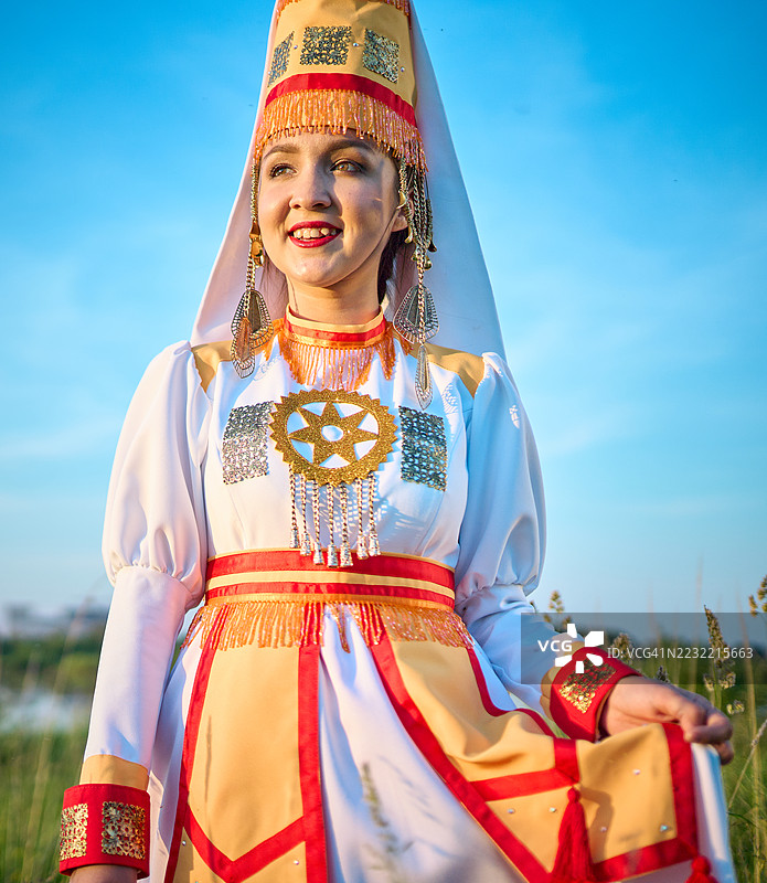 快乐的玛丽年轻女性穿着传统服装，站在池塘旁的草地上图片素材