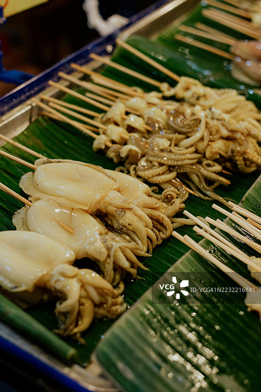 街头美食市场上的香蕉叶烤鱿鱼串图片素材
