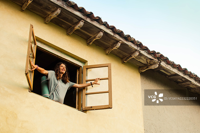 年轻女子探出窗外，享受新鲜空气图片素材