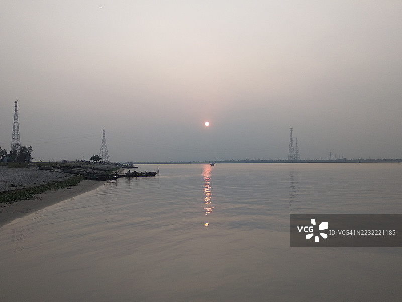 日落时分宁静的河岸，树木和塔楼的剪影，孟加拉国纳尔辛迪区图片素材