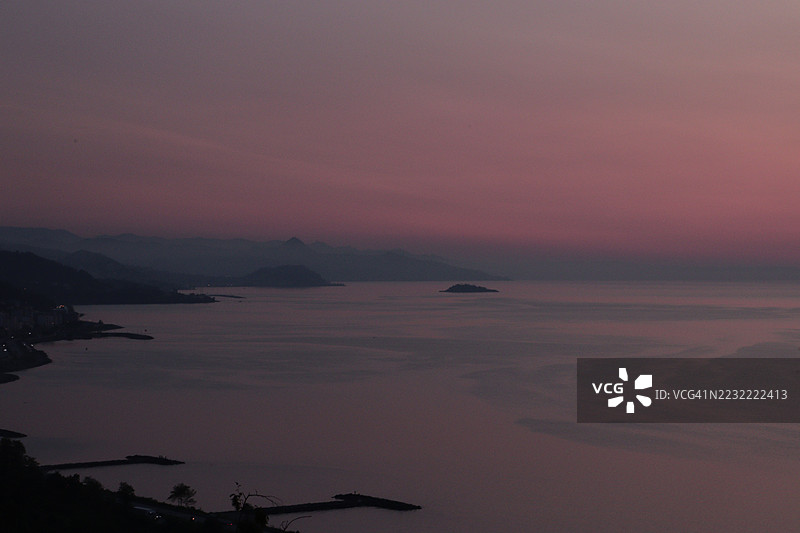 宁静的海上日落与剪影山脉图片素材