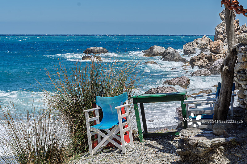 希阿索斯，希腊，岩石海岸旁的椅子和桌子的海岸景观图片素材