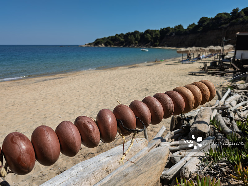 沙滩上绳子上的棕色石头特写，背景是晴朗的蓝天，希腊斯基亚索斯岛图片素材