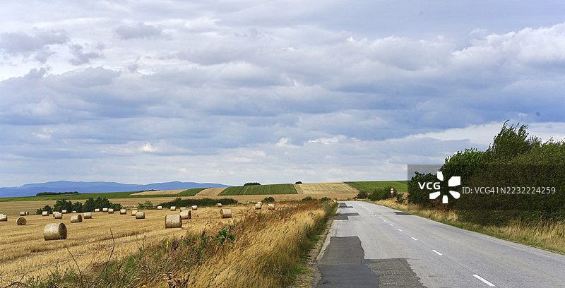 罗马尼亚的麦田间乡村道路在阴云密布的天空下图片素材