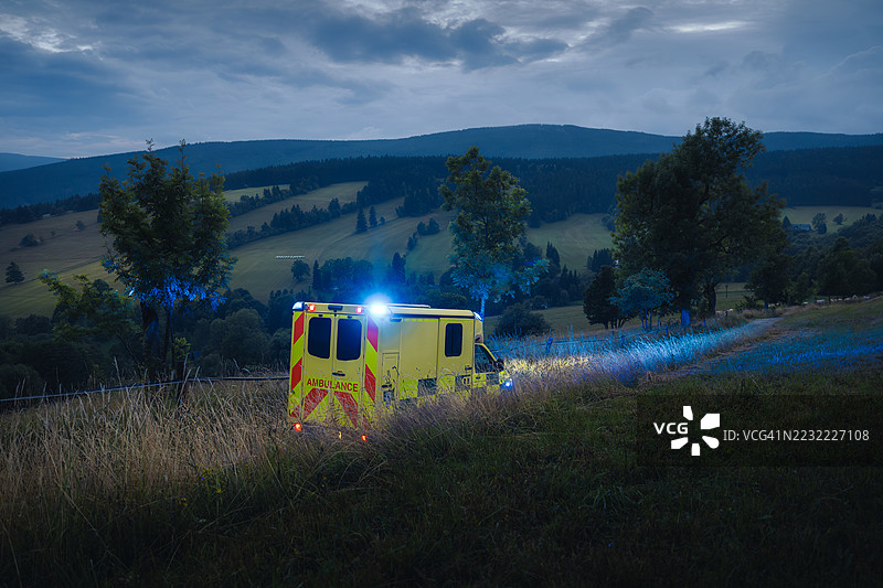 黄昏时分，乡村道路上的闪烁灯光救护车图片素材