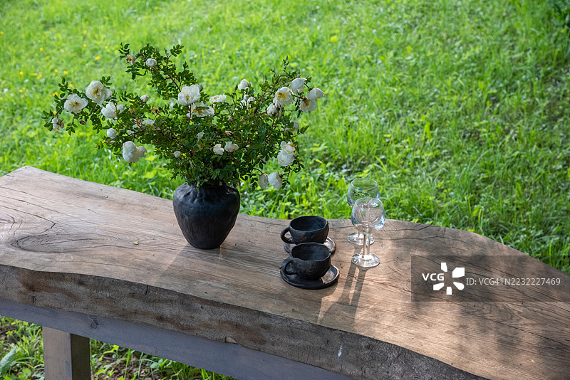 拉脱维亚花园中的乡村木桌，摆放着花卉装饰和杯子图片素材
