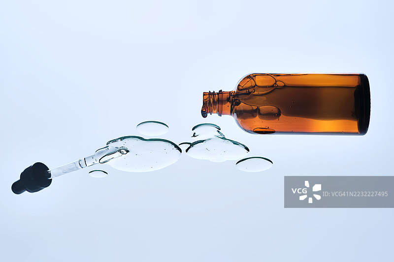 白色背景上的琥珀色玻璃瓶，配有滴管和液体图片素材