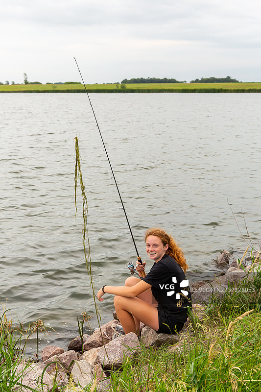 夏天傍晚，少女在岸边钓鱼图片素材