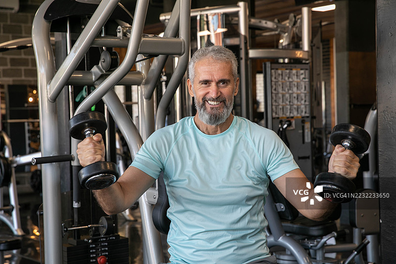 成熟男性在专业健身房锻炼，头发花白图片素材