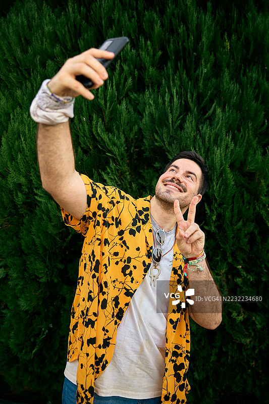 穿着休闲服的男子在户外活动中拍摄有趣的自拍照图片素材