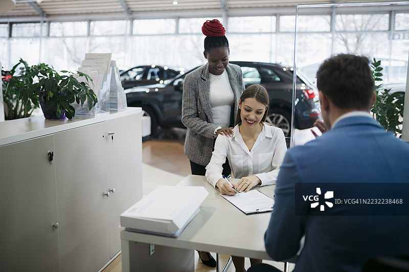 顾客在汽车经销商处与销售人员签署合同图片素材