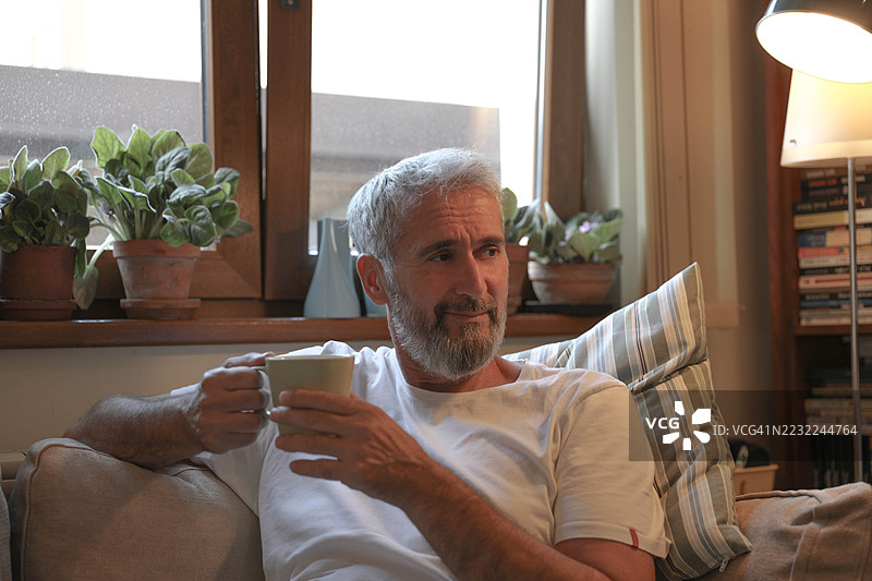 老年男性在舒适的客厅享受早晨咖啡图片素材