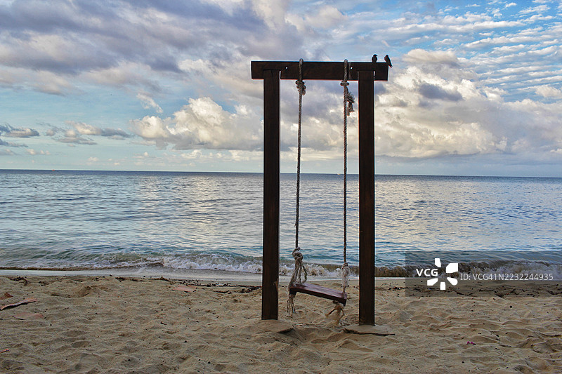 沙滩上的木秋千，天空多云图片素材
