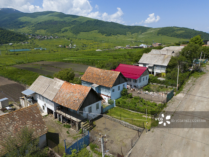 色彩斑斓的房屋排成一行,位于乡间小路上,背景是田野和绿色山丘,鸟瞰图,列门托沃,居住着来自俄罗斯的灵性基督徒普里古尼和莫洛坎,洛里凯特省,亚美尼亚图片素材