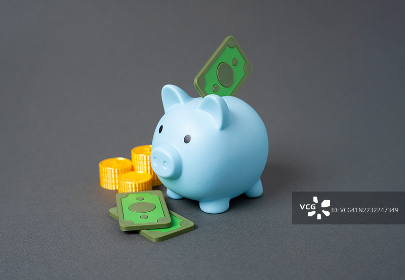 蓝色储蓄罐与硬币和钞票在灰色背景上图片素材