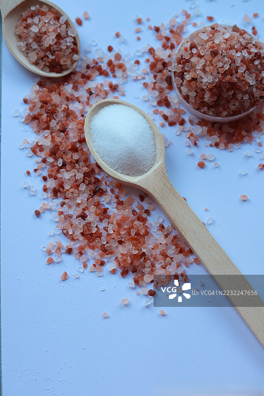 喜马拉雅粉盐和白糖放在白色背景上的木勺中图片素材