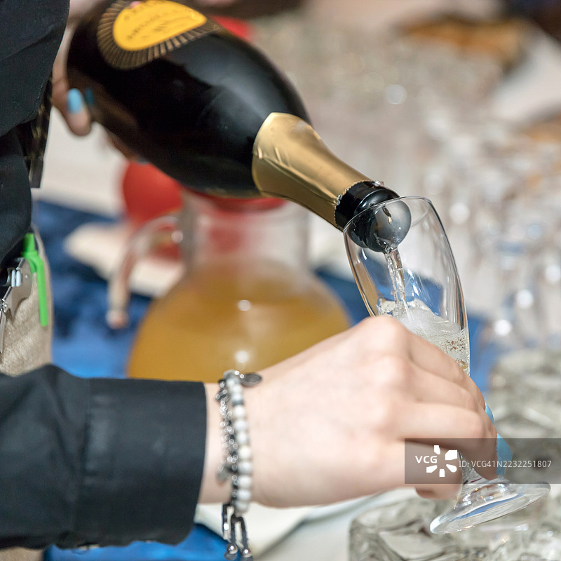 手部特写，正在将香槟倒入酒杯中图片素材