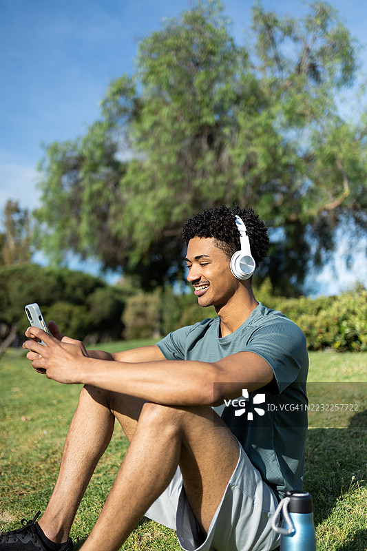 年轻运动员在训练后放松，听手机音乐图片素材