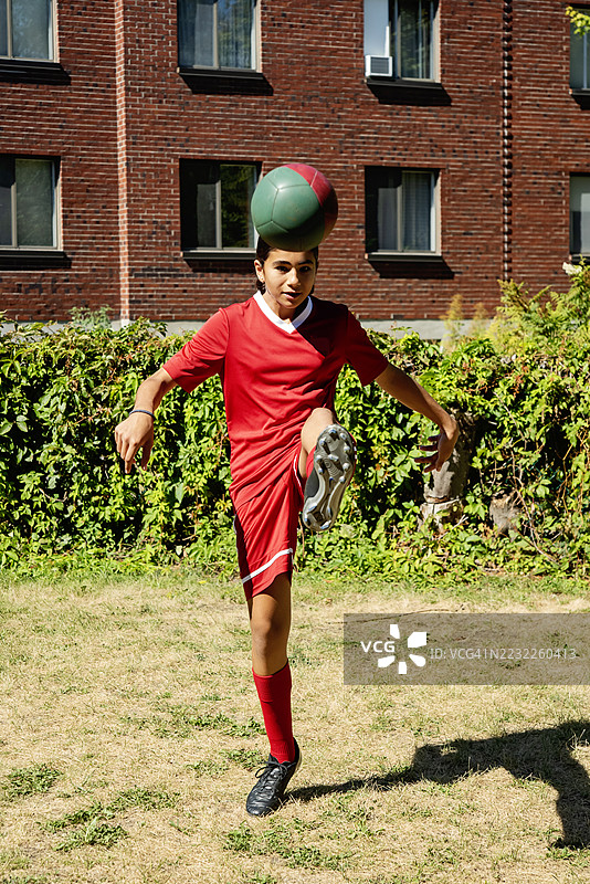 青少年女孩在城市后院自我训练足球。图片素材