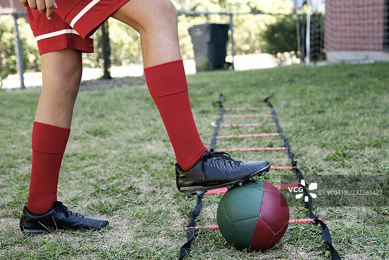 青少年女孩在城市后院自我训练足球。图片素材