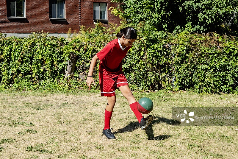 青少年女孩在城市后院自我训练足球。图片素材