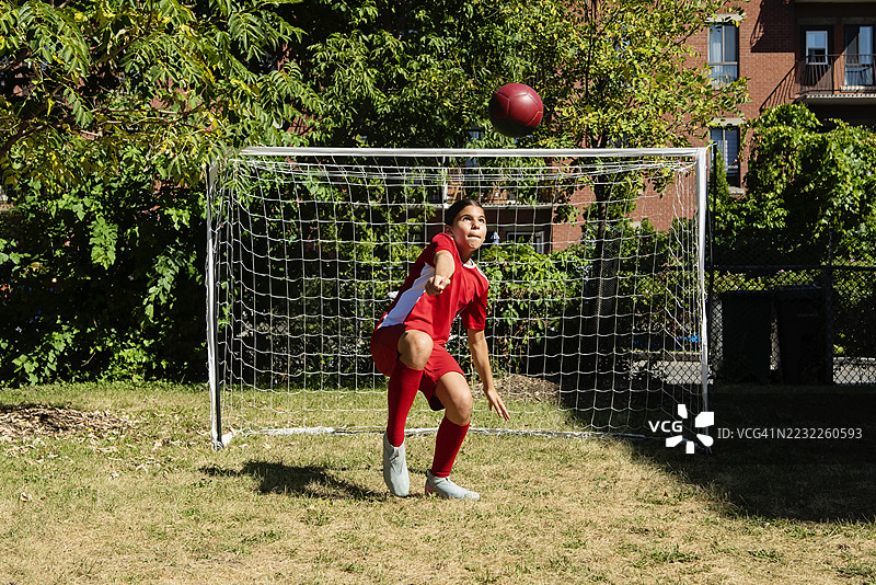 在城市后院训练自己的少女足球运动员。图片素材