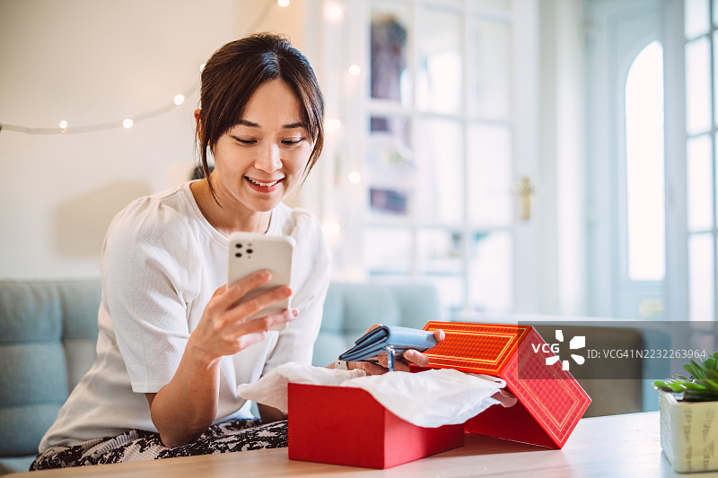 愉快的女性在家中使用智能手机享受网上购物图片素材