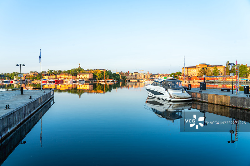 现代游艇停泊在斯德哥尔摩港口平静的水面上，迎接日出。图片素材