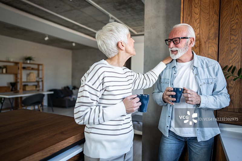快乐的老年夫妇在家中享受咖啡和交谈图片素材