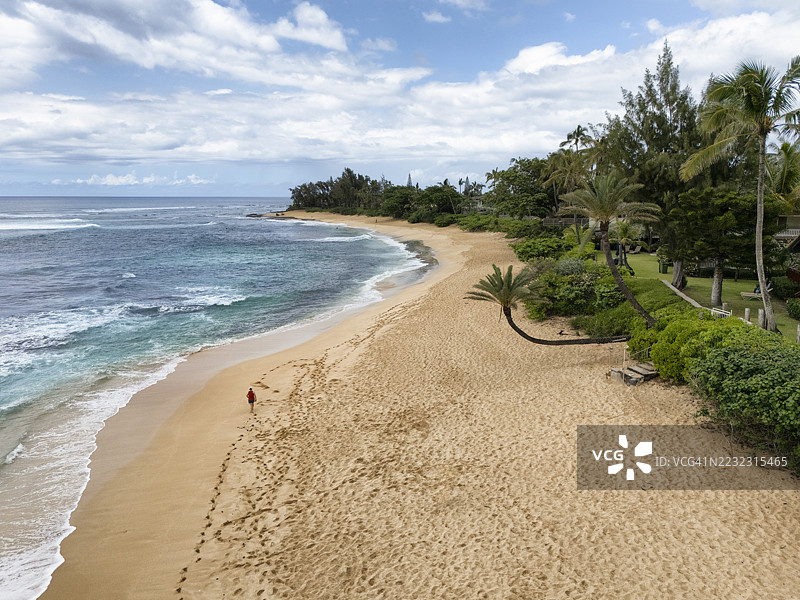 在夏威夷瓦胡岛北岸的日落海滩上散步的男人图片素材