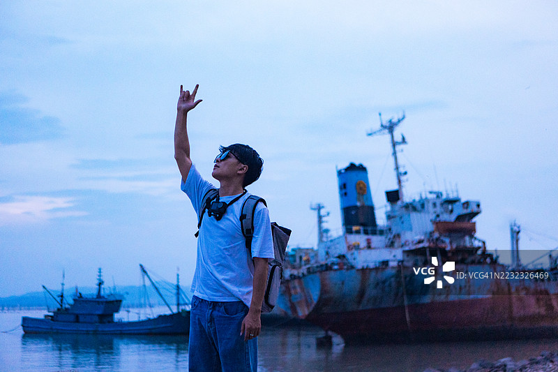 背包客在海边使用颈挂式相机录制视频博客图片素材