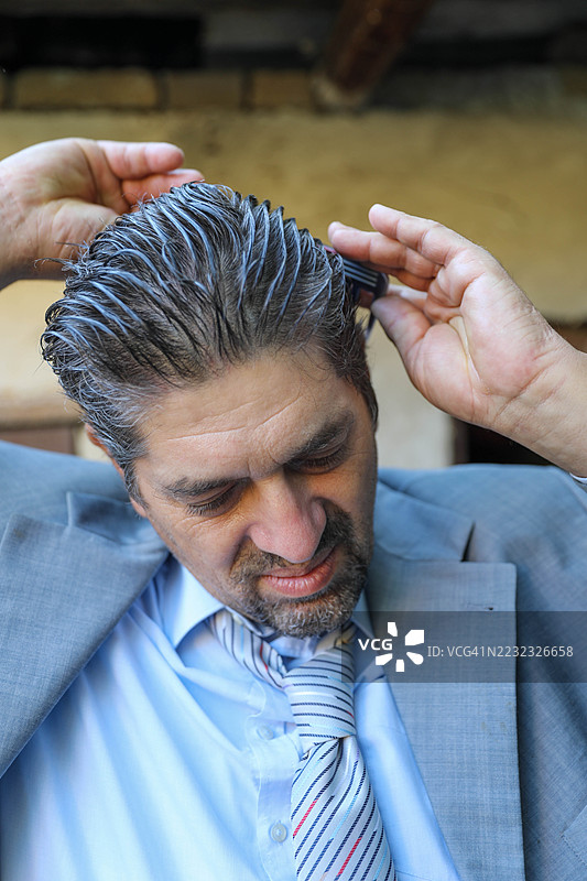 穿着灰色西装的老年男子在户外梳理头发图片素材