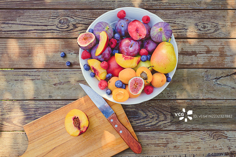 秋天九月，木桌上放着一碗水果，碗里有新鲜切好的桃子。图片素材