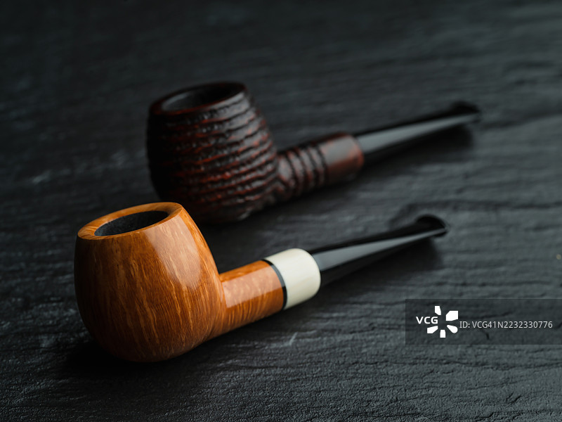 两个苹果形状的管道放在灰色表面上，一个是光滑的，另一个是粗糙的。图片素材