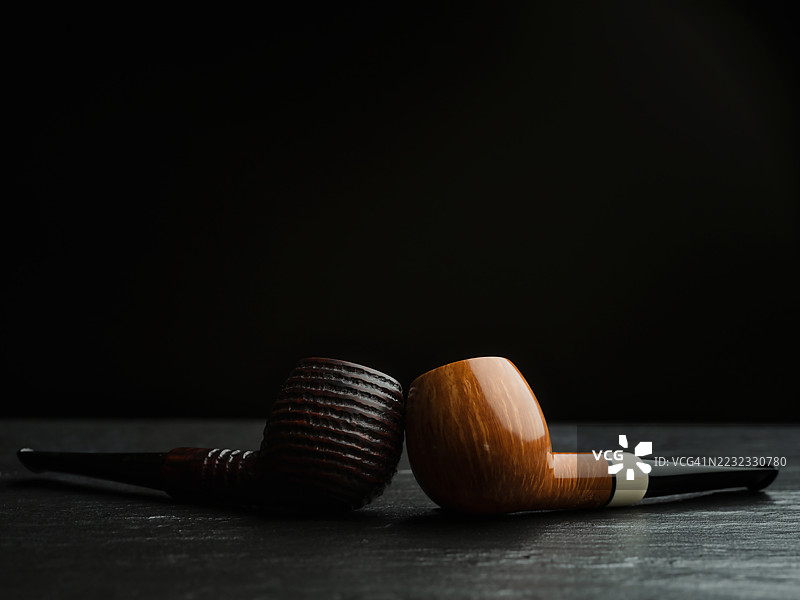 两个苹果形状的管道放在灰色表面上，一个是光滑的，另一个是粗糙的。图片素材