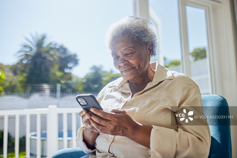 坐在窗边的快乐老年女性特写，手中拿着手机图片素材