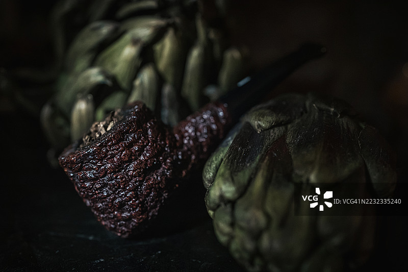 黑色粗糙表面的Castello 55海岩烟斗和一些棕色朝鲜蓟图片素材