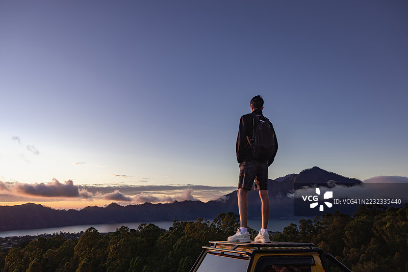 男子在印尼巴厘岛巴图尔山顶徒步旅行时欣赏美丽的日出。图片素材