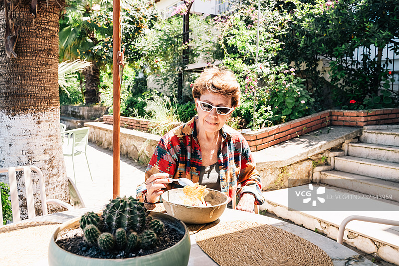 时尚的成熟退休女性在阳光明媚的户外咖啡馆享受生活。图片素材