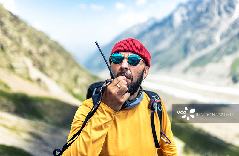 在风景如画的山脉环境中使用对讲机交流的徒步旅行者图片素材
