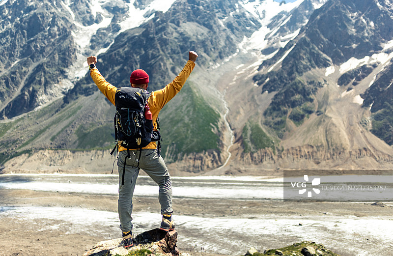 胜利的登山者站在山顶，俯瞰壮丽的雪山谷图片素材