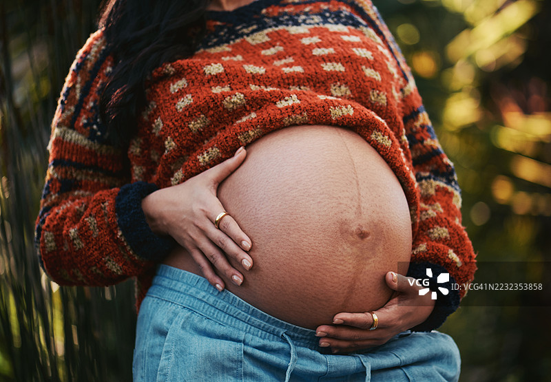 户外期待中的母亲轻抚孕肚图片素材