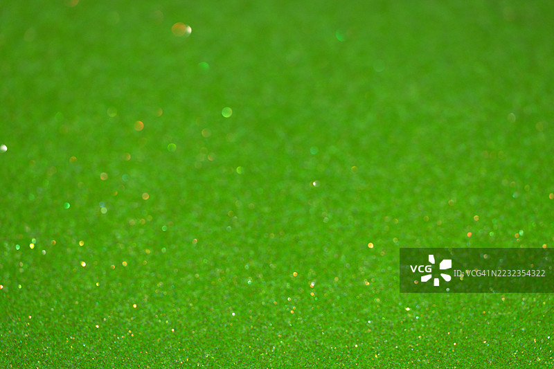 绿色闪闪发光的亮片背景与金色散景灯光图片素材