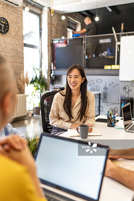 年轻的亚洲女商人在与同事开会时微笑图片素材