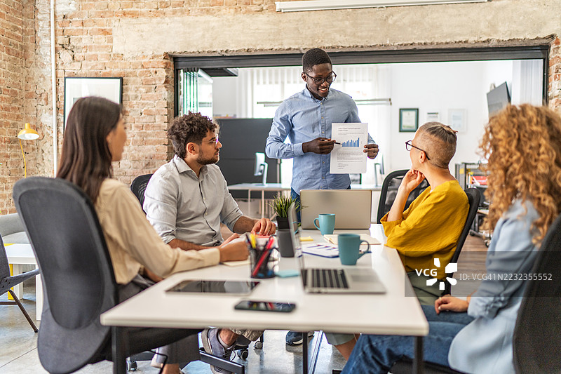 年轻经理在会议室向多元化的同事们展示公司战略图片素材