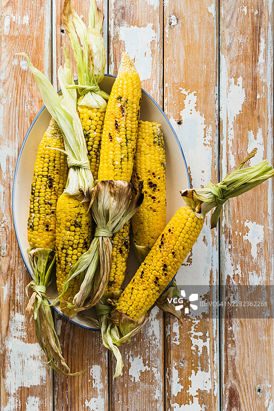 带壳烤玉米棒配绿色香草黄油图片素材
