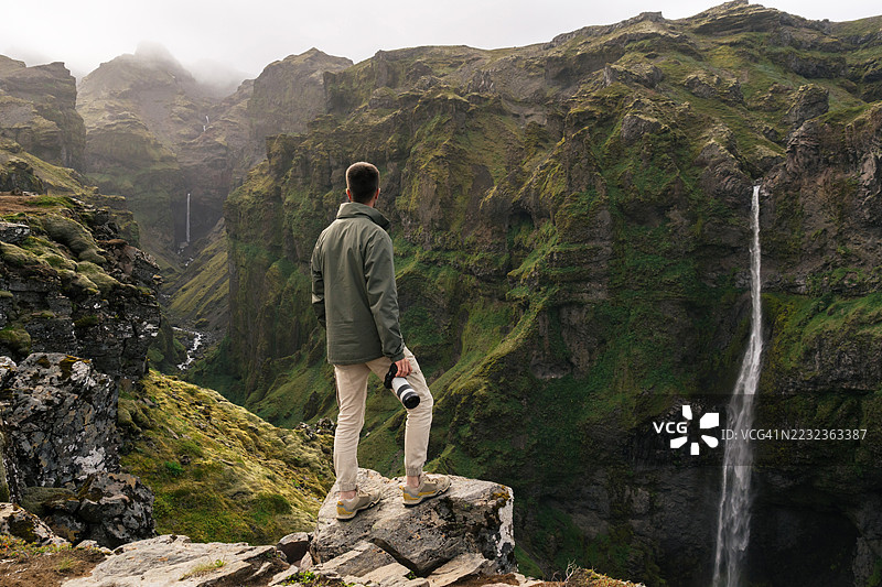 年轻男子手持相机欣赏穆拉格柳夫峡谷图片素材