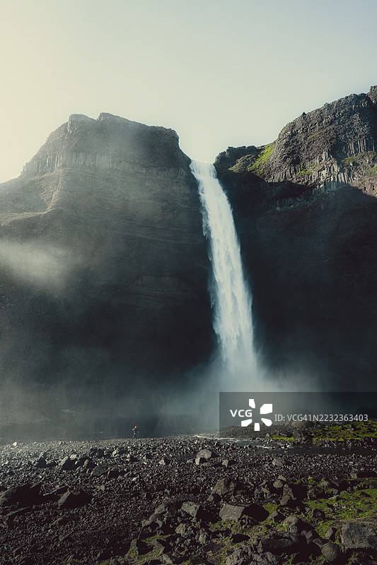 在冰岛瀑布下行走的男人图片素材