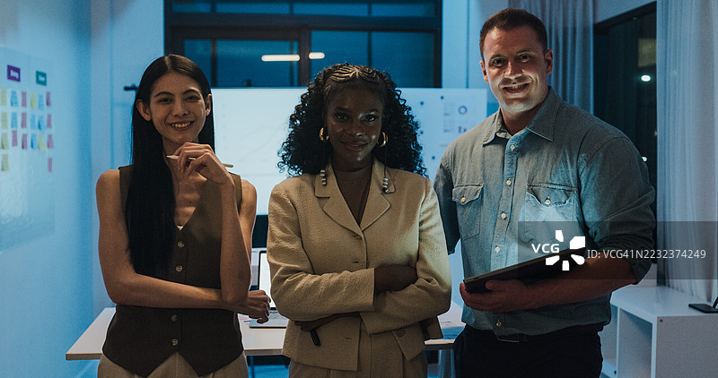 自信多元化的金融团队在现代办公室夜间召开商务会议，微笑着看向镜头，站在一起。市场营销策略分析，股票市场交易，财务顾问。图片素材