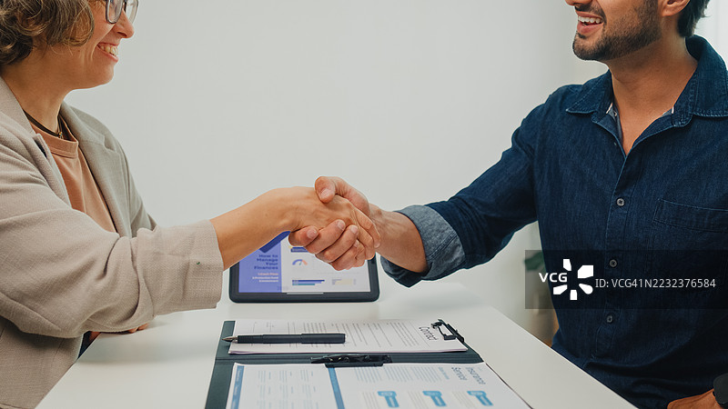 年轻夫妇在家客厅与财务顾问签署财务协议的特写镜头。财务规划与生活方式概念。图片素材